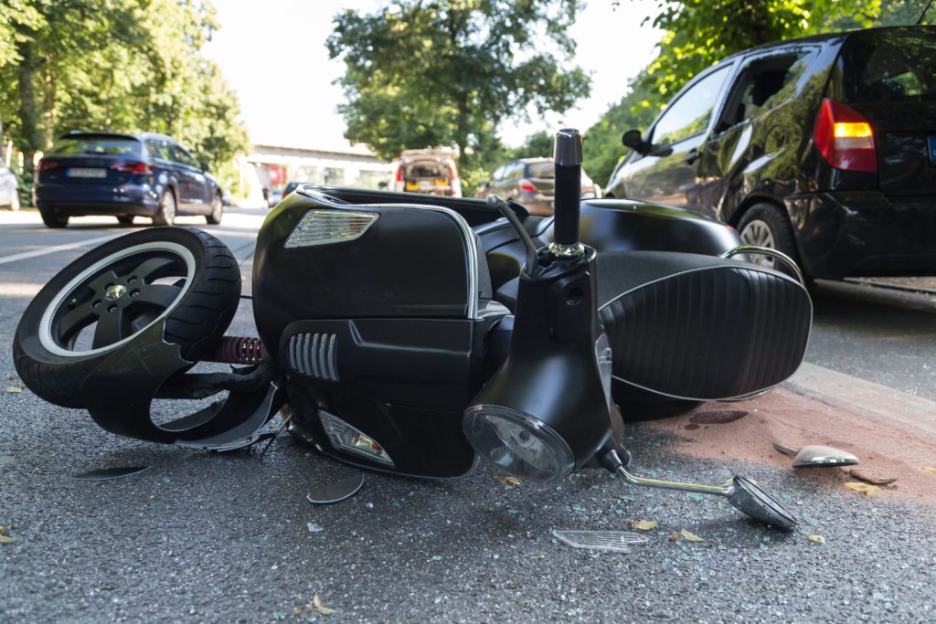 Moped accident happening along the road.