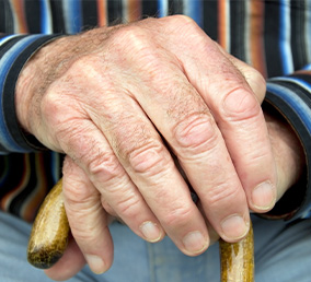 an elderly person with their hands on their cane