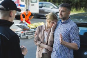 Couple involved in car accident interviewed by the police officer.