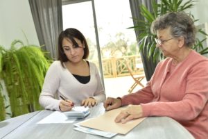 Woman helping old woman in paperworks.