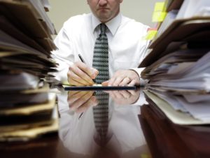 Man surrounded by stack of paperwork.