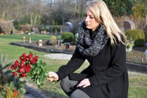 Sad woman offering flowers in the cemetery.