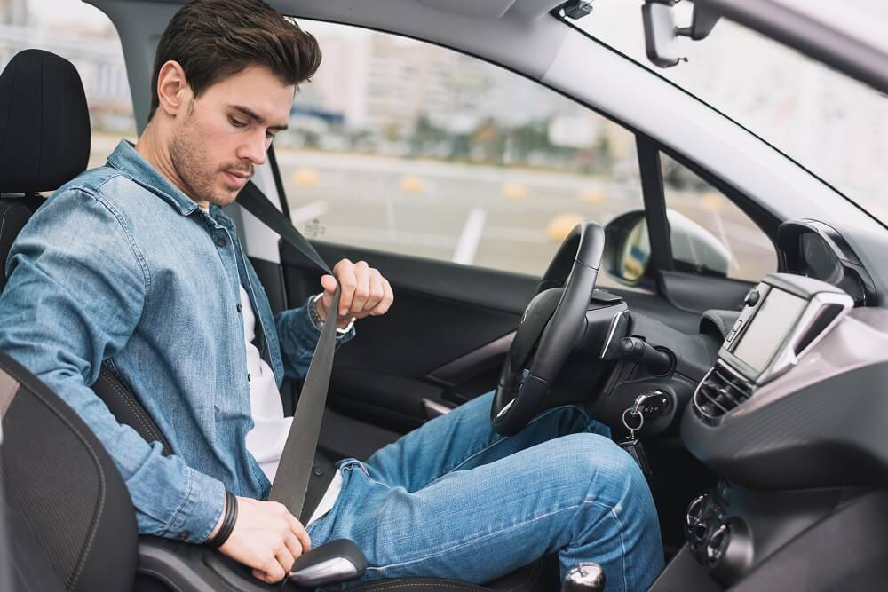 Young driver fastening seatbelt for safety.