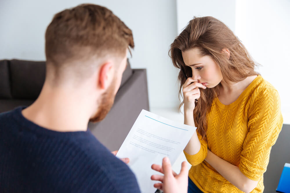 Sad couple talking about their huge debt on how to pay them.