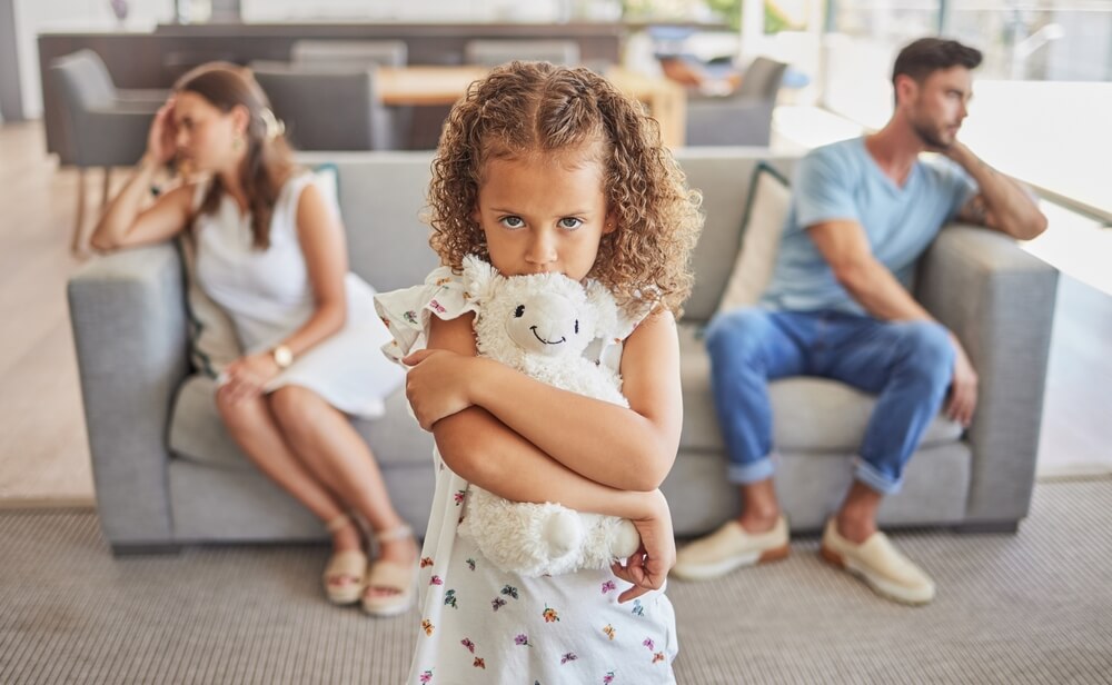 Sad little girl on her parents fighting.