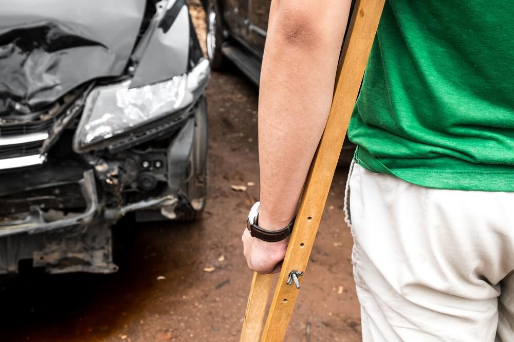 Injured driver on crutches from severe car accident.