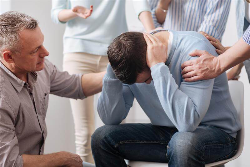 Group of coworkers encouraging their distressed friend.