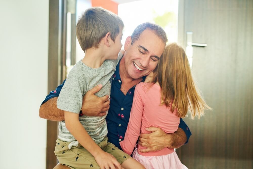 Father hugging his children in the front door for welcome, smile or excited for love, care and bonding.